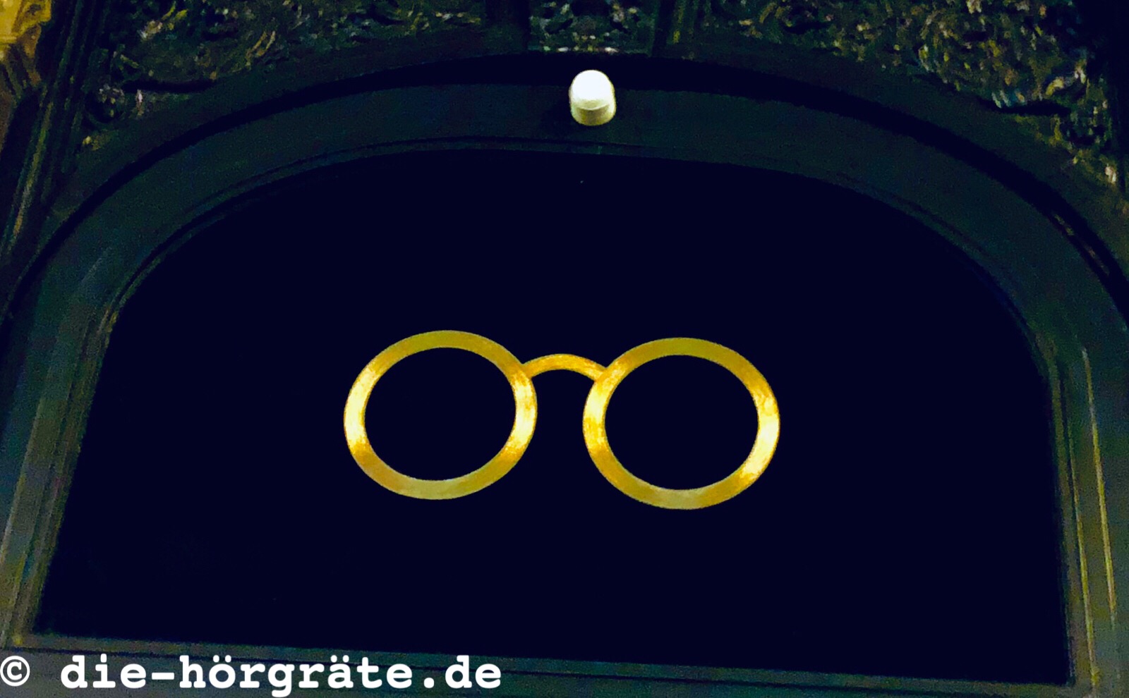 goldfarbene Brillenfassung über Optiker-Tür